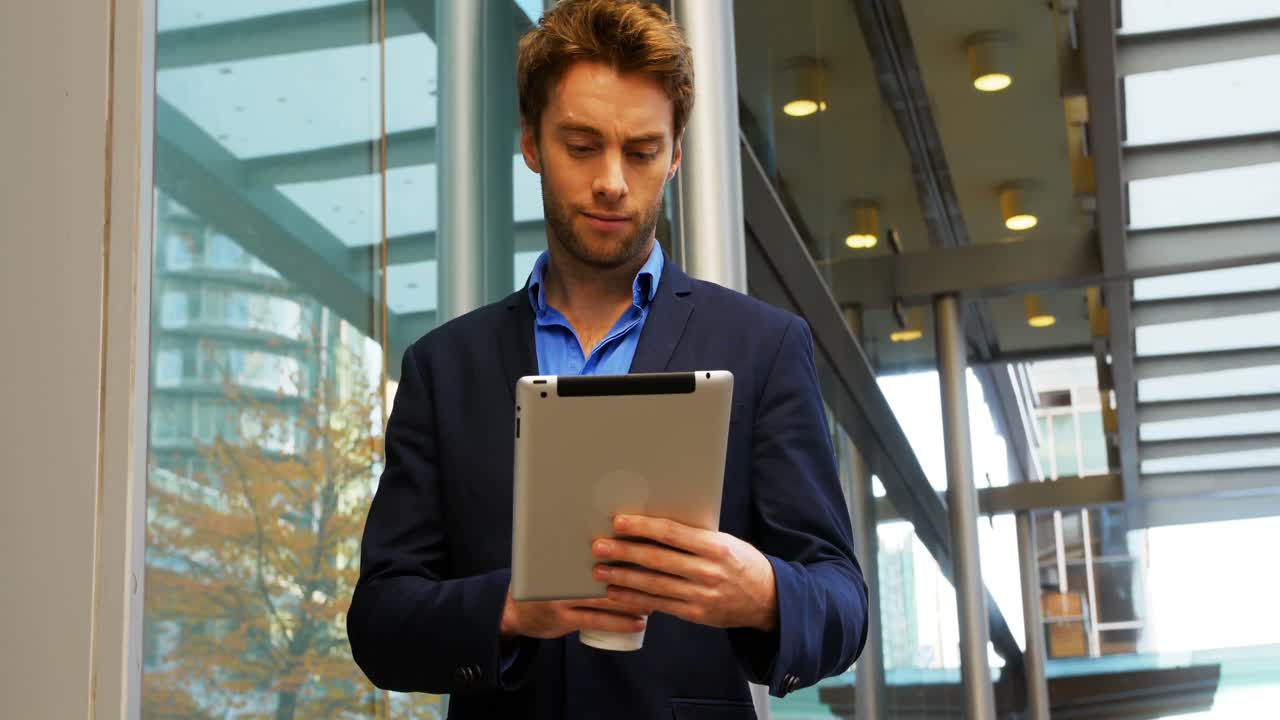 Forretningsmand holder kaffekop og bruger digital tablet