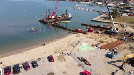 Descending-Drone-shot-of-Hingham-Harbor-showing-Digger-Boat-and-cars-along-shoreline