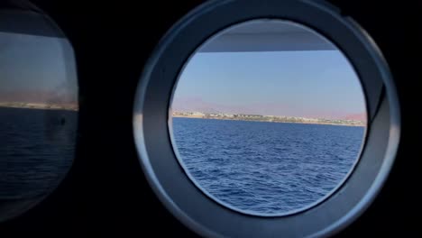 view from the window of a cruise ship porthole showing the mountains of egypt at sunset