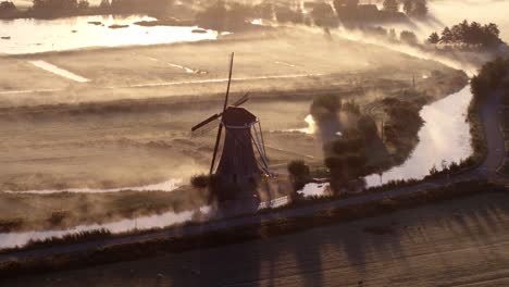 misty sunrise over dutch windmill