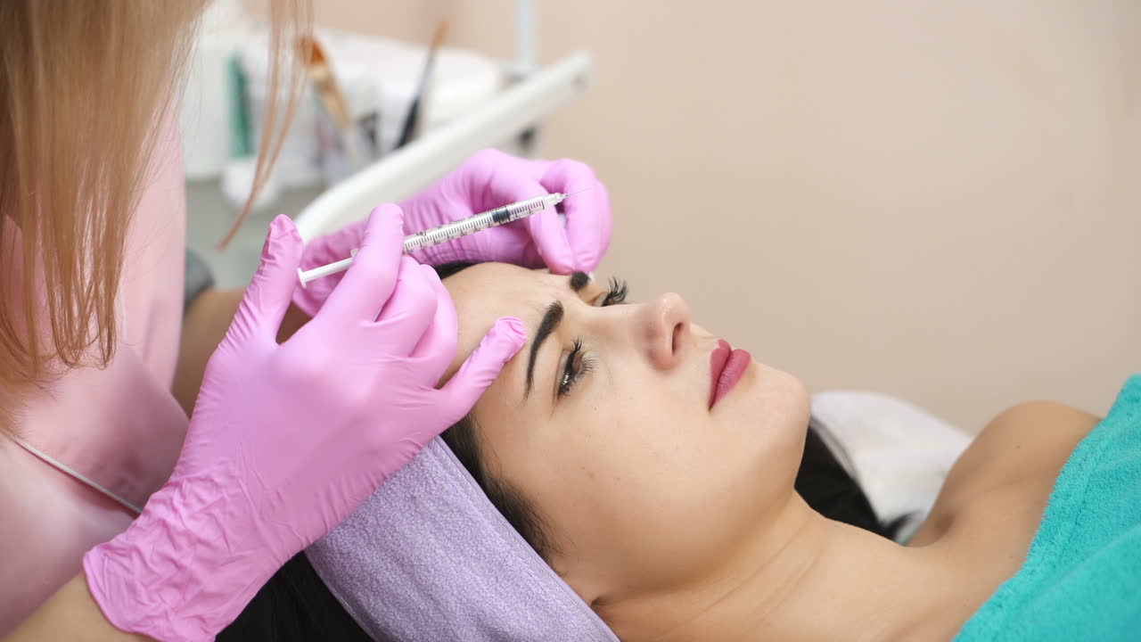 Young beautiful dark-haired woman gets rejuvenating facial injections. Work of the cosmetologist. Aesthetic cosmetology.