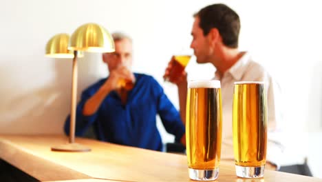 two men interacting with each other while having beer at counter