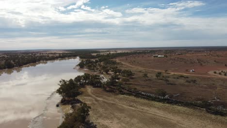 drone ascending over a massive cattle farm in australia showing the farm house in the background as well as the lake