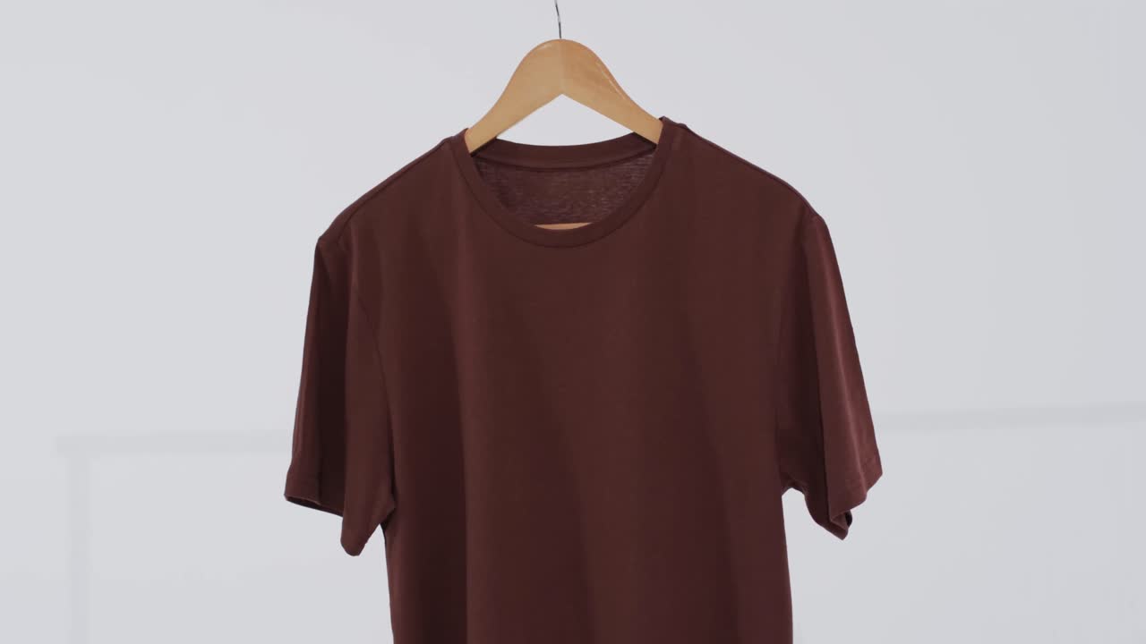 Video de camiseta marrón en percha y espacio para texto sobre fondo blanco