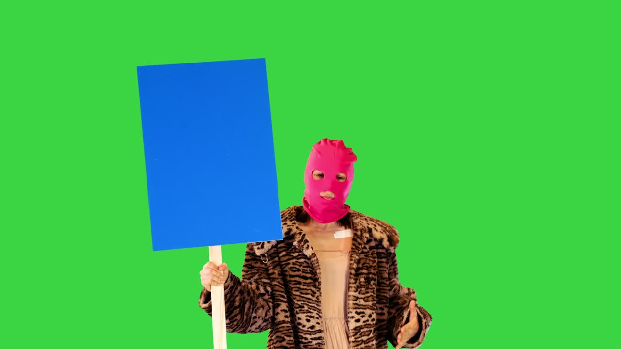 Pige i lyserød elefanthue danser let, holder et banner og peger på det på en grøn skærm, Chroma Key.