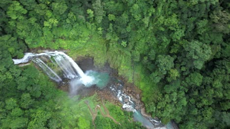 órbita aérea de la cascada eco chontales cayendo en un estanque natural rodeado de un denso bosque tropical verde, costa rica