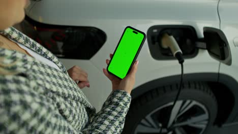 mujer usando teléfono inteligente mientras ev cobra