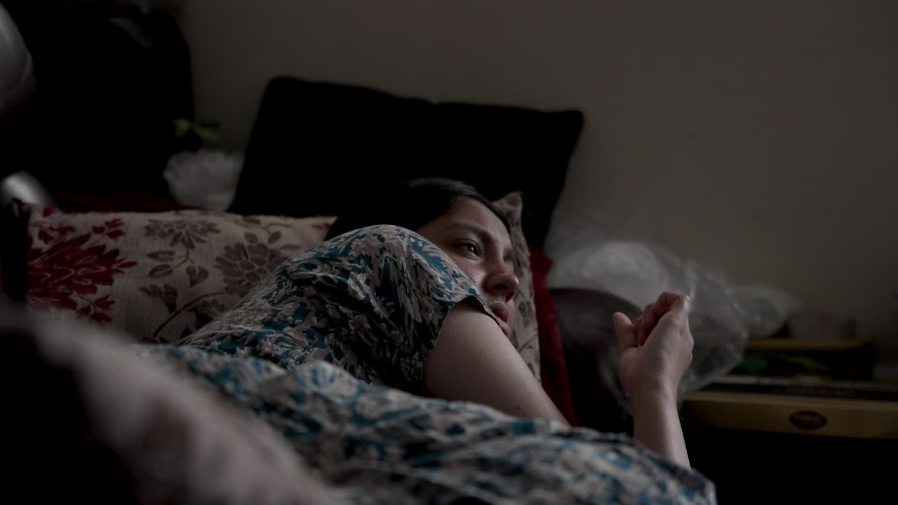 una toma de cerca de una mujer asiática tendida en un sofá inmóvil pensativa mientras juguetea ansiosamente con los dedos