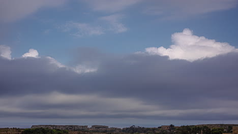 disparo de lapso de tiempo del movimiento de las nubes sobre las tierras altas rocosas y las casas del pueblo en un día nublado