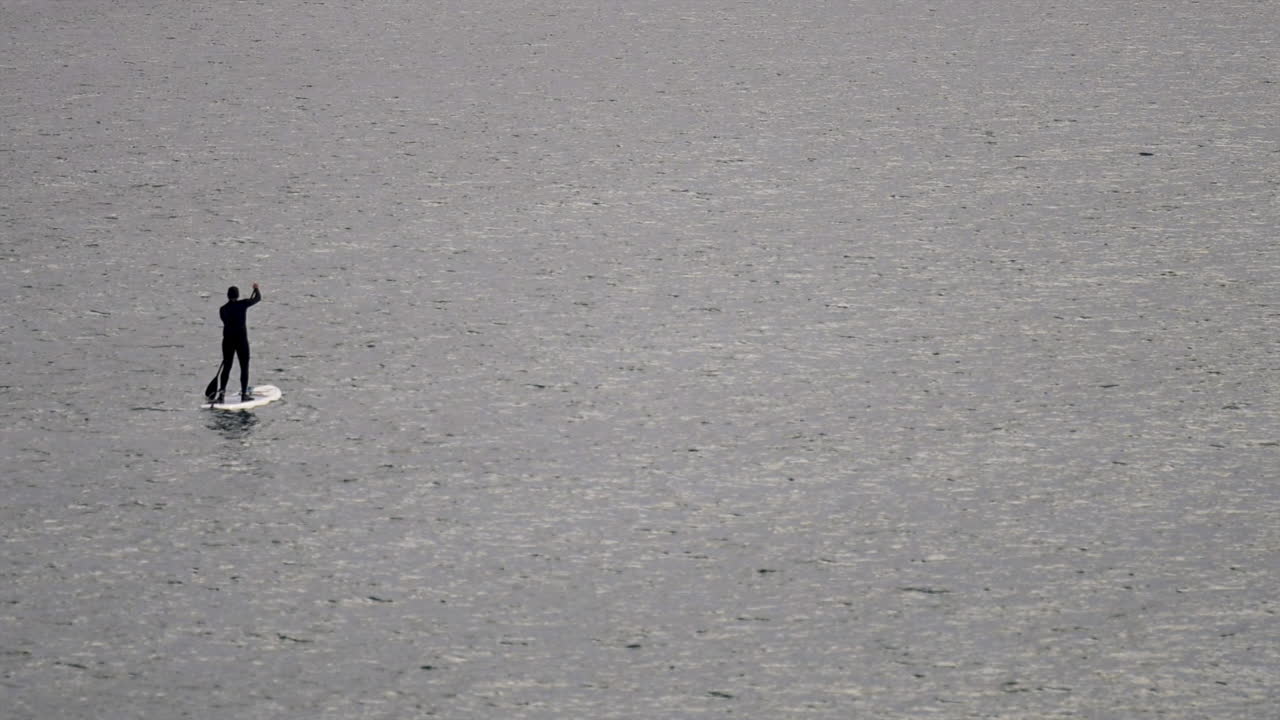 Distant view of a man stand up paddleboarding on the sea