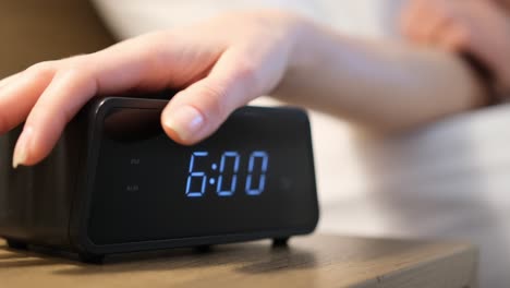 Close-up of an alarm clock on a bedside table in a bedroom