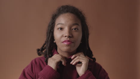 portrait of charming african-american woman fixing shirt collar