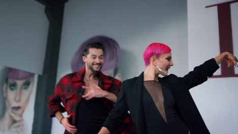 energetic dancers raising hands in class. smiling couple dancing for camera.