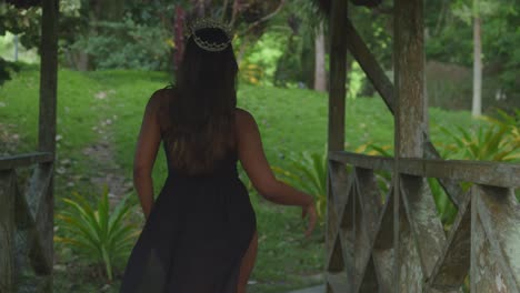a young girl in a black dress walks through the arches of a historical site.