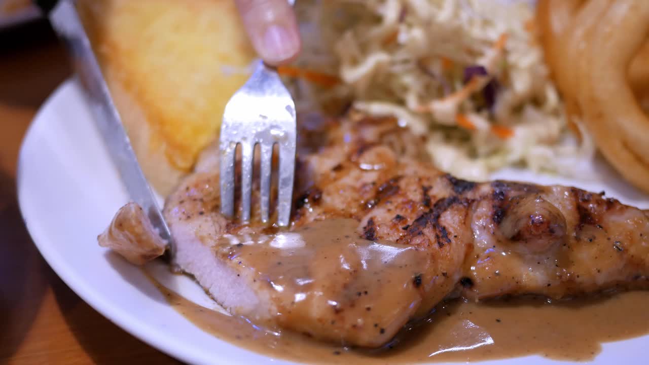 cortar un poco del filete de pollo servido en una bandeja con ensalada de verduras, anillos de cebolla y un pan tostado con mantequilla en un restaurante en bangkok, tailandia
