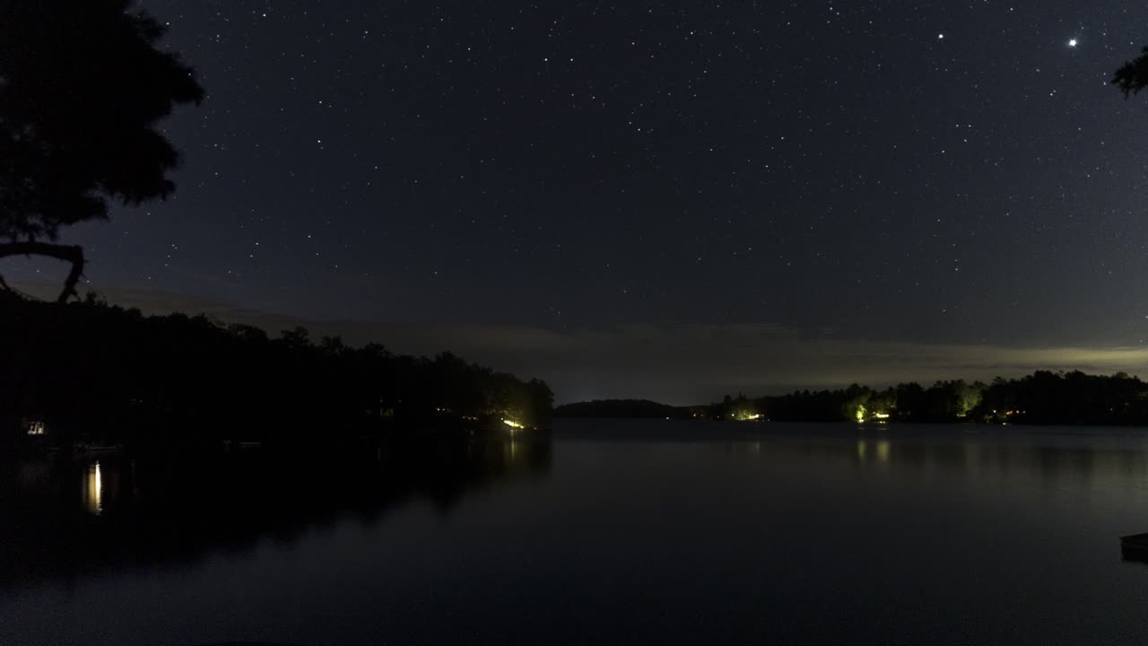 noite estrelada timelapse sobre lago sereno com silhueta da costa