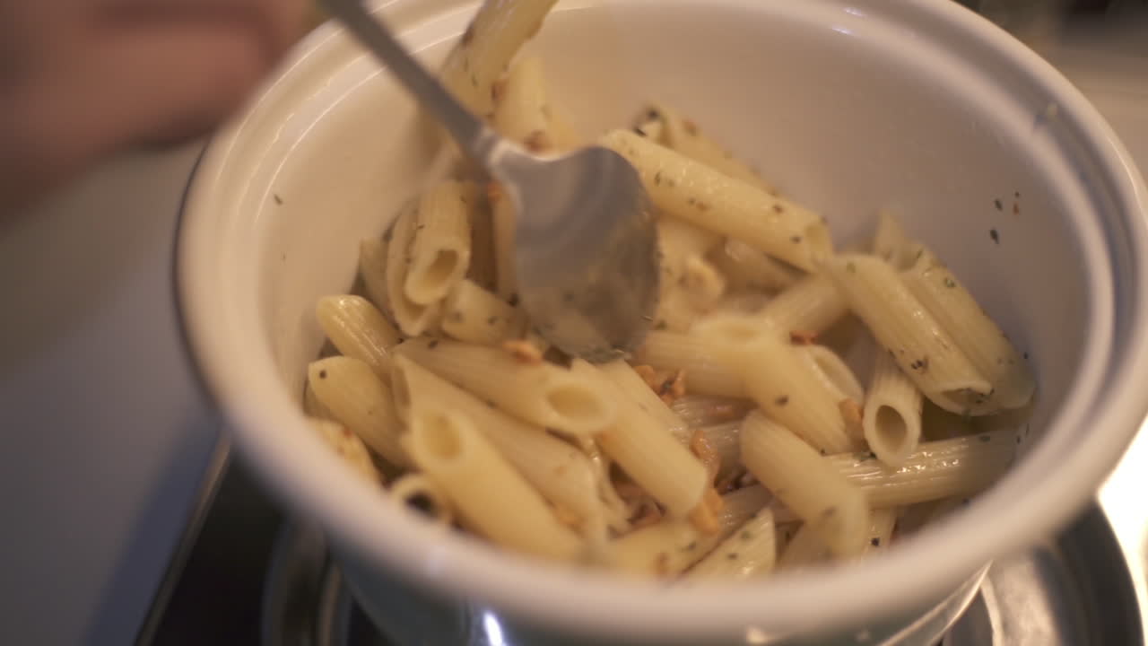 primer plano de pasta penne, perejil, ajo y aceite de oliva revueltos y mezclados