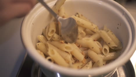 Close-up-of-penne-pasta,-parsley,-garlic-and-olive-oil-stirred-and-mixed-together