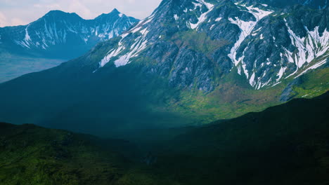 Aerial-Over-Valley-With-Snow-Capped-Mountains-In-Distance