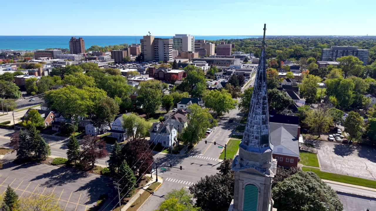 órbita aérea del campanario de una iglesia en Waukegan, Illinois, con el skyline de la ciudad al fondo