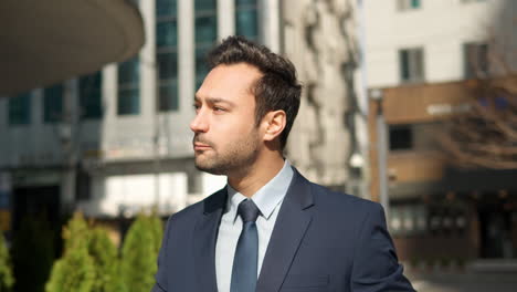 portrait of handsome happy business man in suit eating tasty donut while walking in city street on the way to work in slow motion