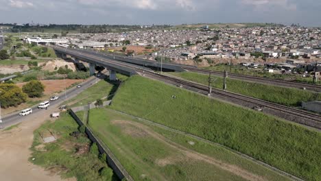 En-Estas-Concisas-Imágenes-Aéreas-En-4k,-Un-Dron-Ascendente-Captura-El-Paisaje-Urbano-De-Un-Municipio-Adyacente-A-Las-Vías-Férreas-Y-Carreteras-De-Gautrain-En-Johannesburgo,-Sudáfrica.