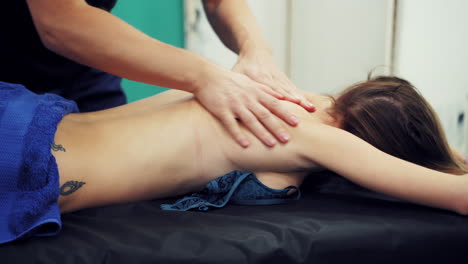 therapist doing curative healing massage. partial view of massage therapist doing massage to patient on massage table in spa salon