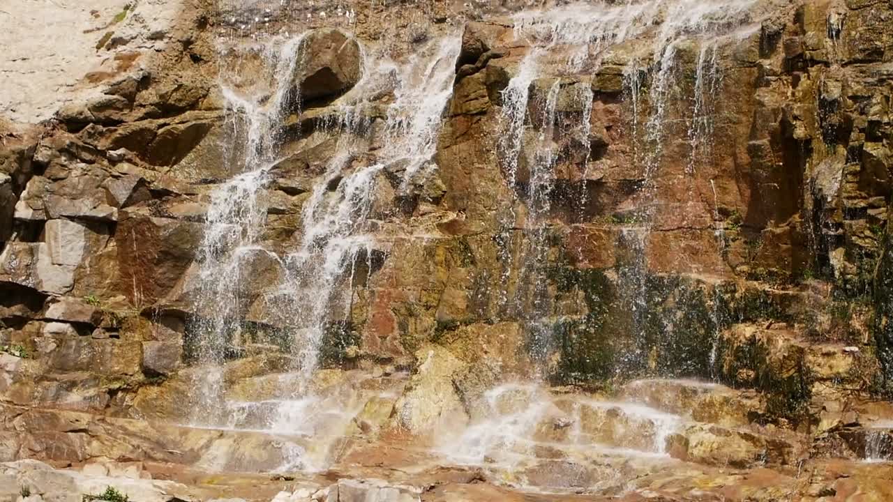 hermosa cascada desde un acantilado en el bosque. 4k video de agua que fluye, arroyo que fluye entre las piedras. arroyo en el bosque