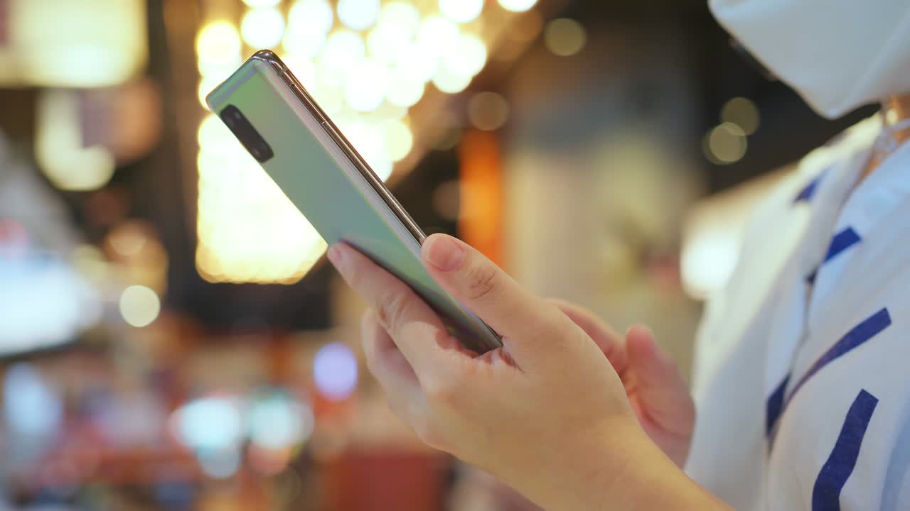mano femenina de cerca usando comunicación de teléfono inteligente con bokeh ligero de fondo de candelabro