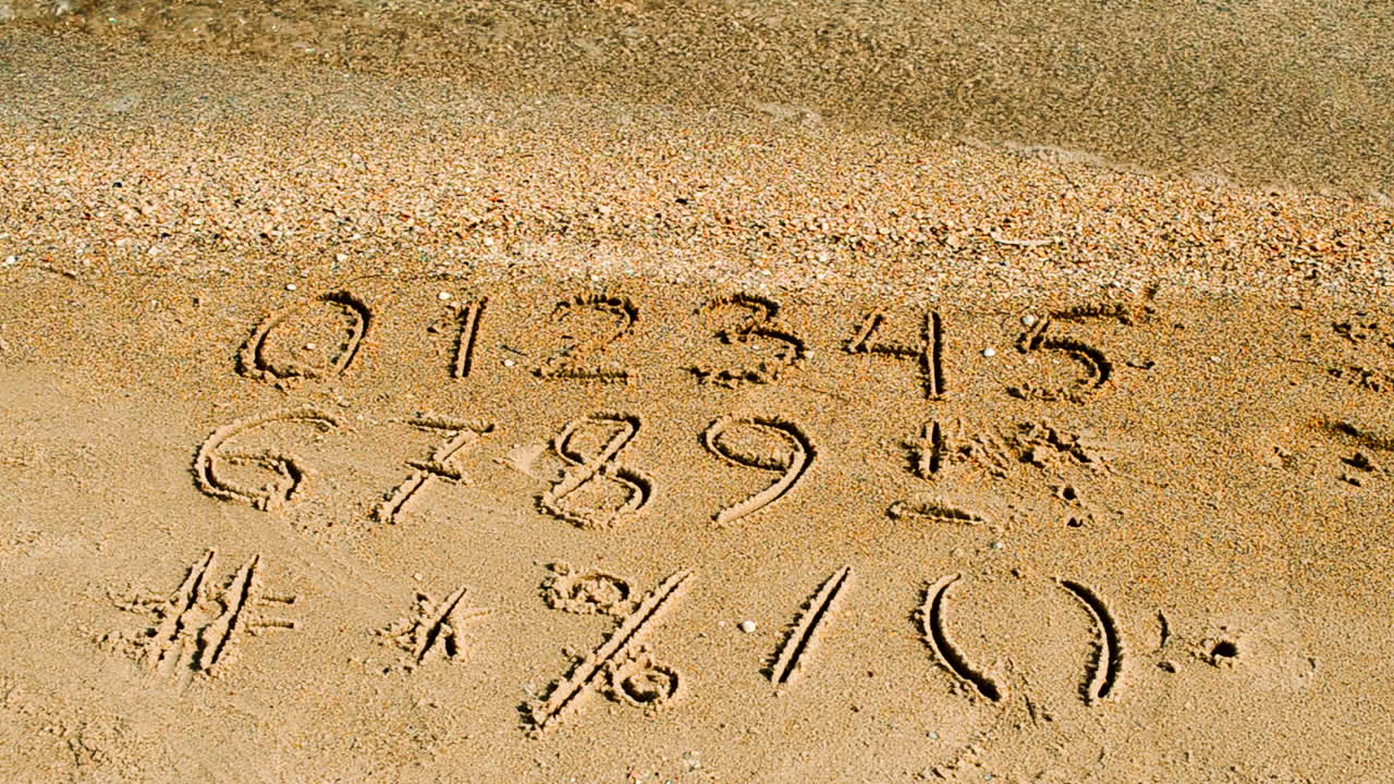 Cifre og tegn skrevet i strandsand. Optagelse på stranden