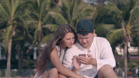 tremendous couple sits under bright sunlight against palms