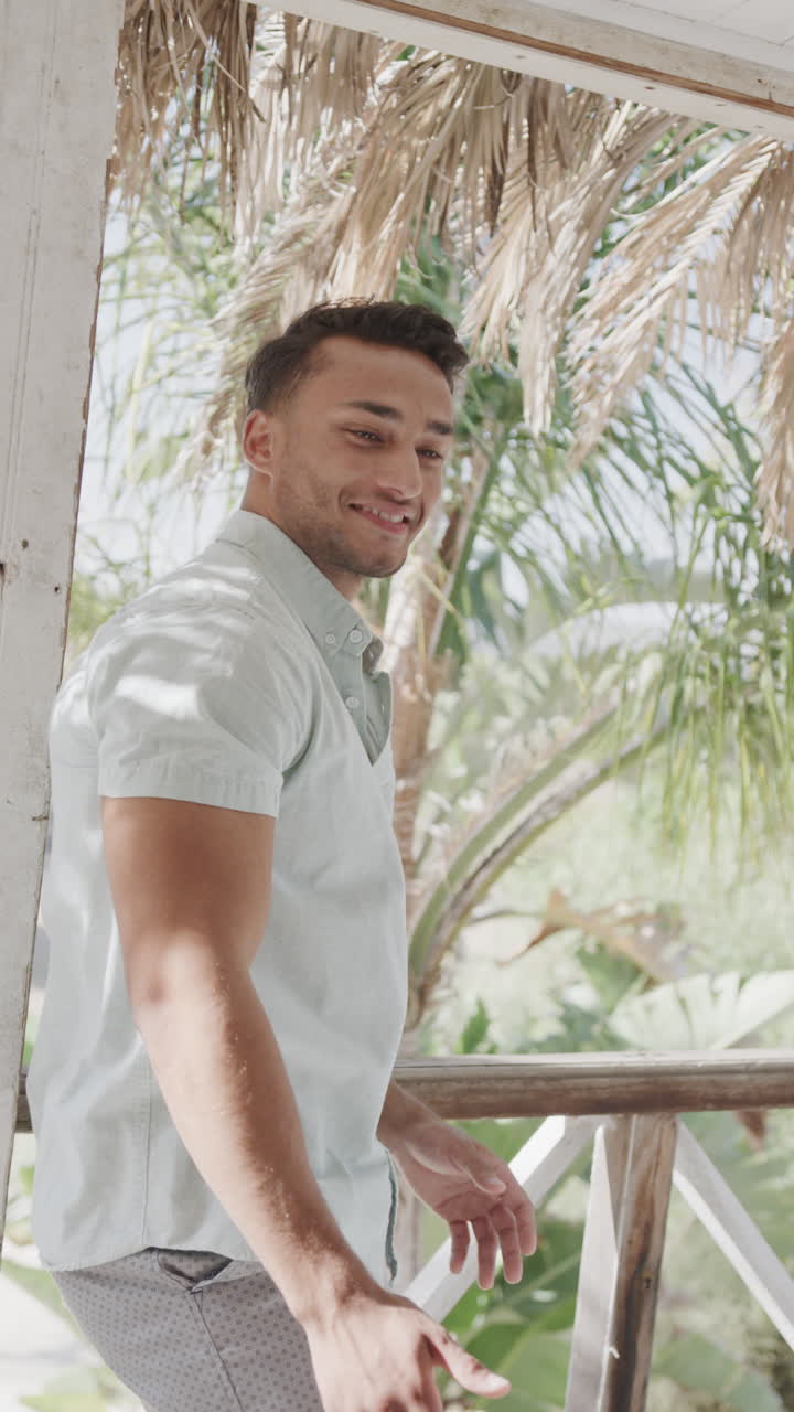Vertical video of happy diverse couple embracing on sunny beach house porch, slow motion