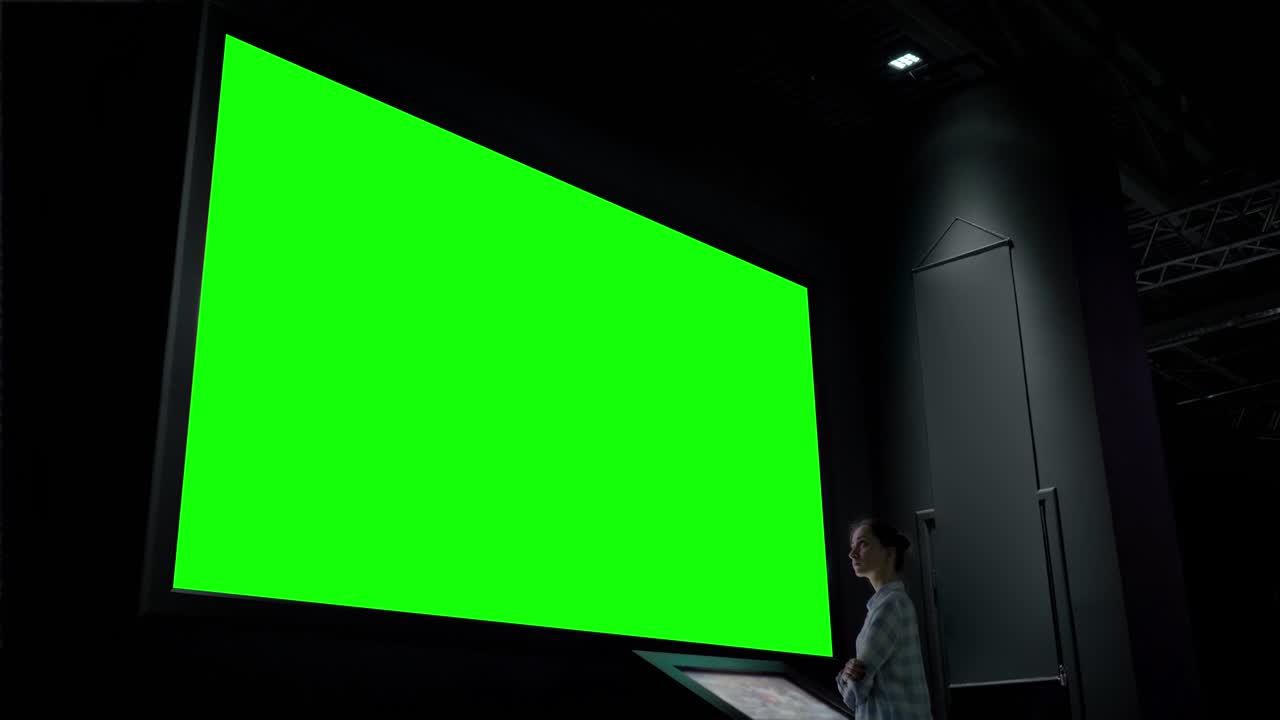 pantalla verde concepto clave de croma - mujer mirando a la pantalla de pared grande vacía