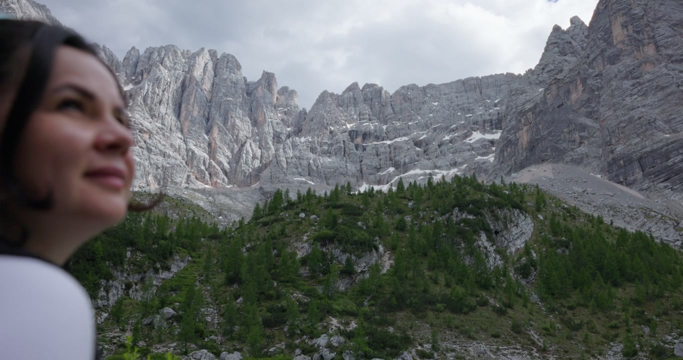 Una donna escursionista guarda il Lago di Sorapis verso le cime rocciose delle montagne nelle Dolomiti italiane, Italia. Ripresa al rallentatore