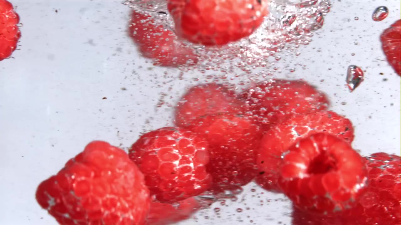 Slow Motion of Fresh Red Raspberries Floating in Water with Bubbles