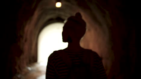 una mujer caminando por un túnel oscuro.