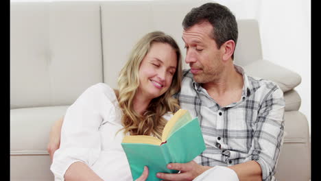 marido leyendo un libro con su esposa embarazada