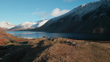 Volando-Sobre-El-Paisaje-Invernal-Revelando-Un-Lago-Oscuro-Con-Montañas-Cubiertas-De-Nieve-En-El-Distrito-De-Los-Lagos-Wasdale-Reino-Unido