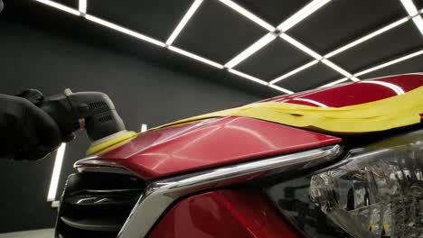 worker polish a red car. car detailing - men are using machinery car polishers maintenance to remove marks repair according to the surface of the car's paint before contin