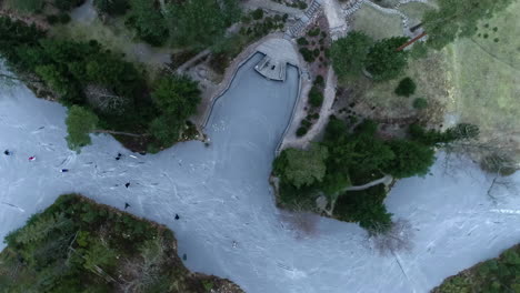 Aerial-top-down-view-of-many-people-ice-skating-on-a-frozen-lake