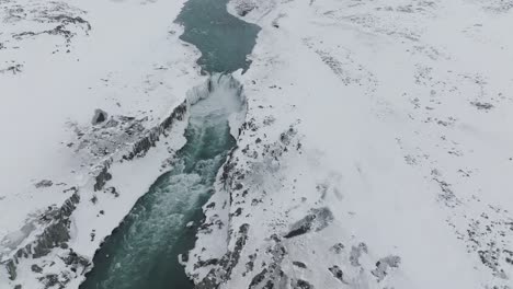 snowy iceland cliffs above river and dettifoss waterfall in winter, aerial