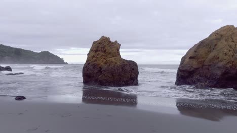 rising from rock cluster to reveal secluded beach on wild rugged east coast of new zealand