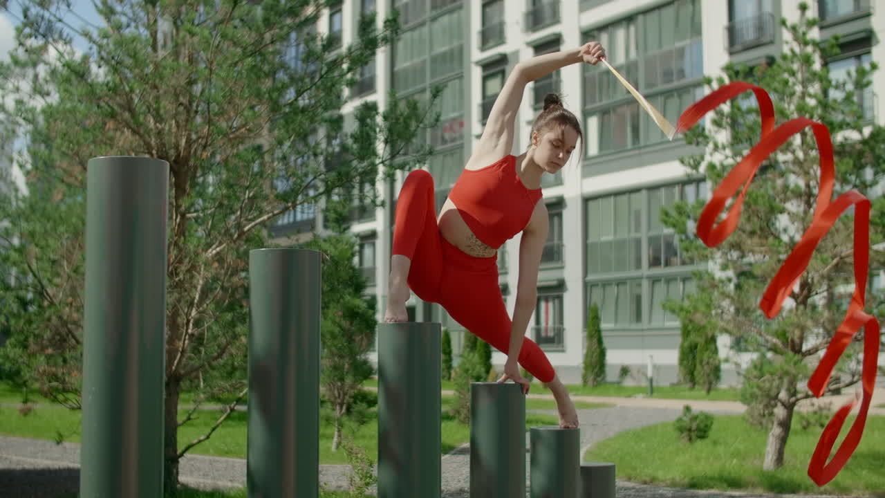 Woman performing ribbon dance on columns in urban setting