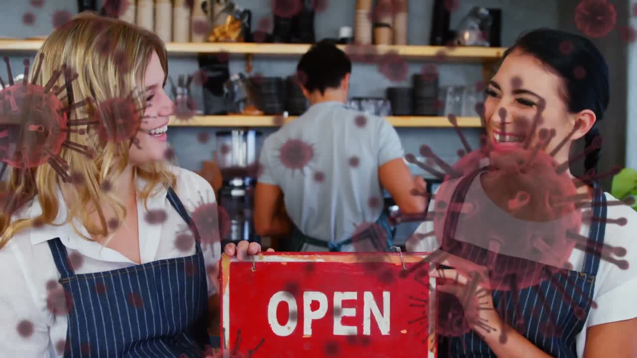 animación de células macro covid-19 flotando sobre dos felices cocineras de raza mixta y caucásicas