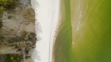 people walking along the chlapowo beach near the baltic sea at the foot of a cliff, poland, aerial top-down view