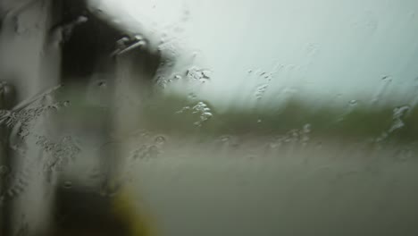 close-up of raindrops on a window with a blurred view of the outdoors, capturing a rainy day ambiance