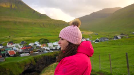 Female-tourist-enjoys-the-view-of-Gjogv-village-at-sunset,-Faroe-Islands