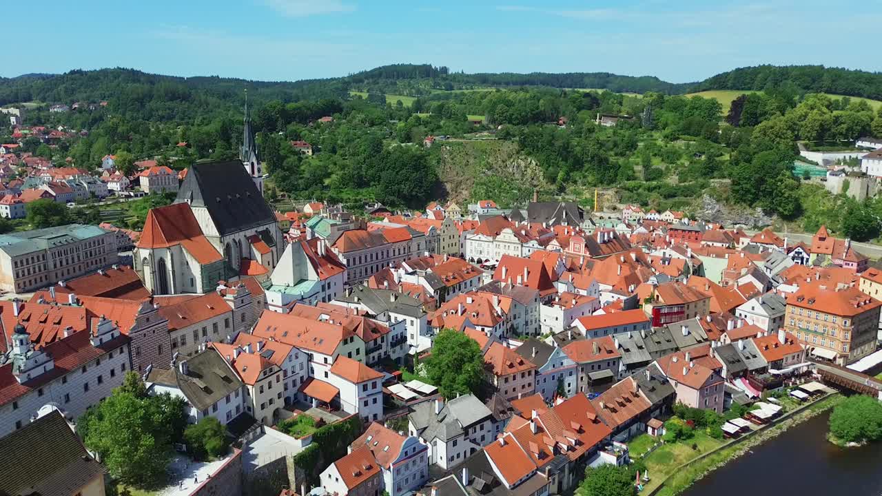 Tarihi bir şehir merkezinin üzerinde yavaşça alçalan bir hava çekimi. Birçok eski bina ve ortada bir kale bulunuyor. Hava güneşli ve bazı bulutlar var.