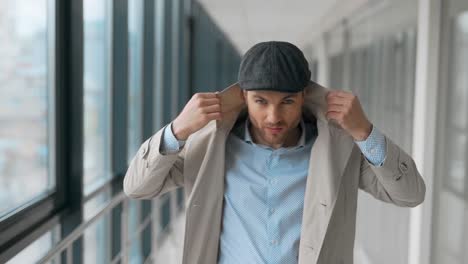 hombre brutal con estilo posando frente a la cámara en una gabardina