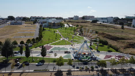 vista aérea de la rueda de la fortuna con un parque más verde como fondo en seixal, portugal - disparo de un dron